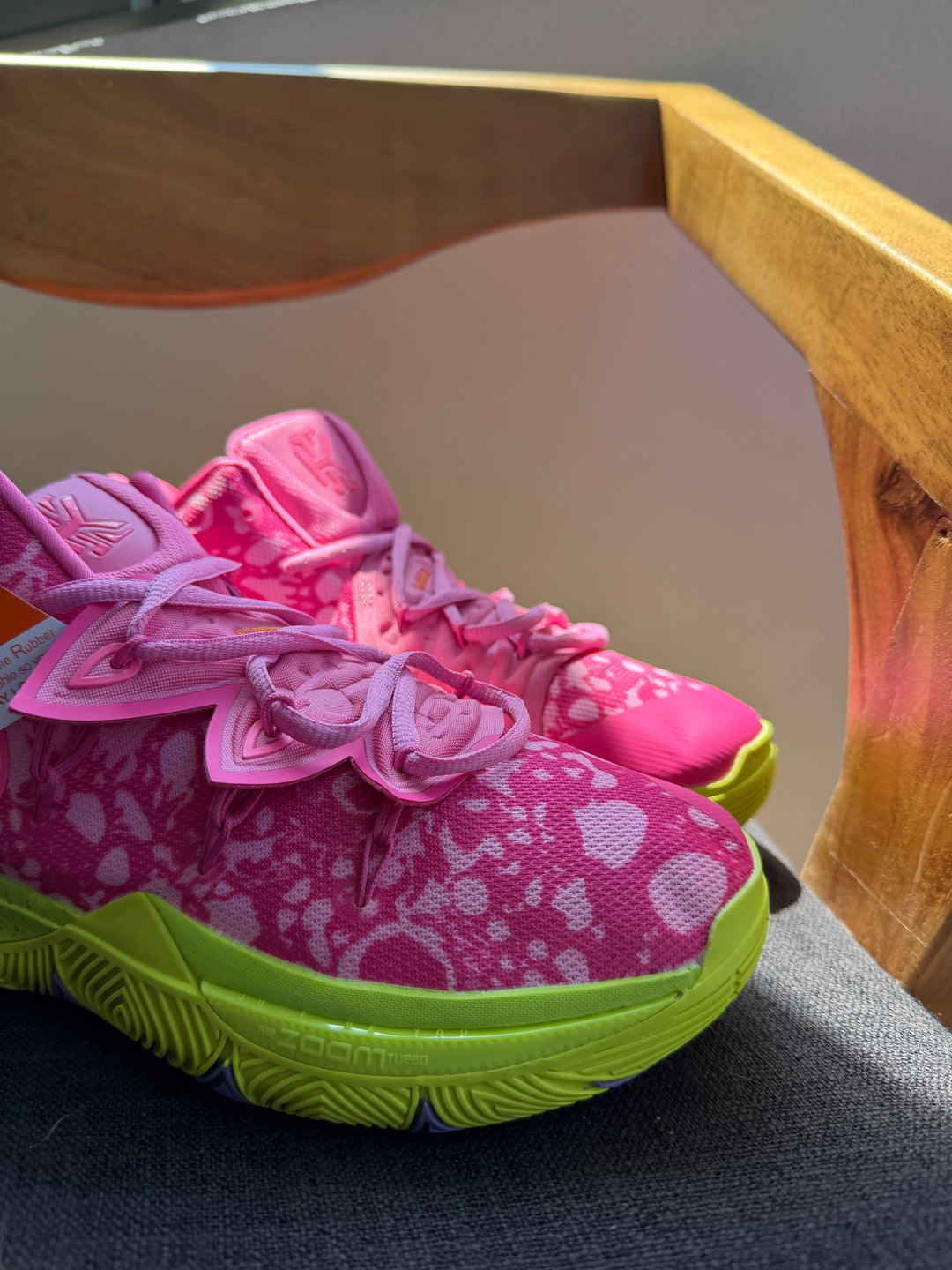 Nike Kyrie 5 Patrick Star tenis de básquet en color rosa con detalles verdes sobre una superficie de madera.